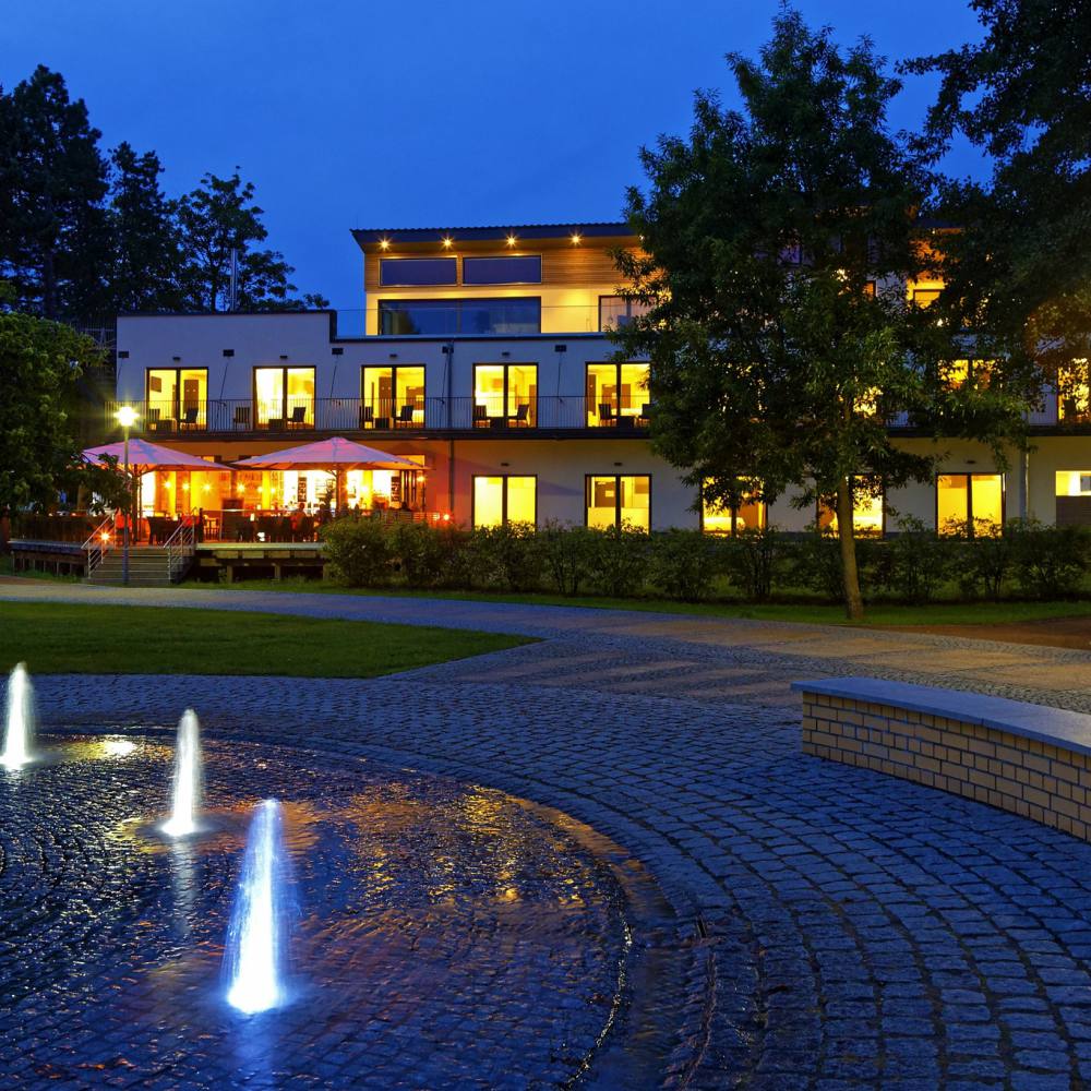 Hotel am Kurpark Zinnowitz am Abend mit beleuchteten Wasserfontänen im Kurpark