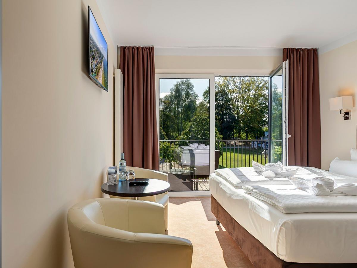Deluxe Doppelzimmer mit Sitzecke und offener Balkontür, Blick ins Grüne