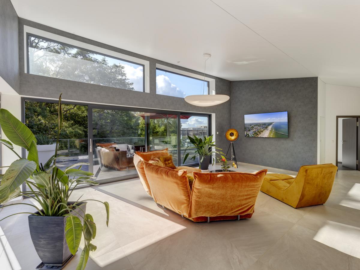 Wohnraum der Penthouse-Wohnung mit hohen Fenstern und Zugang zur Dachterrasse