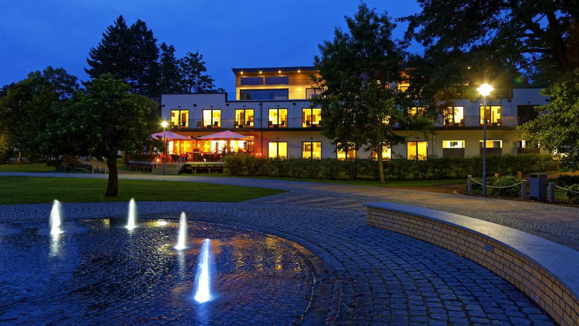 Hotel am Kurpark Zinnowitz am Abend mit beleuchteten Wasserfontänen im Kurpark