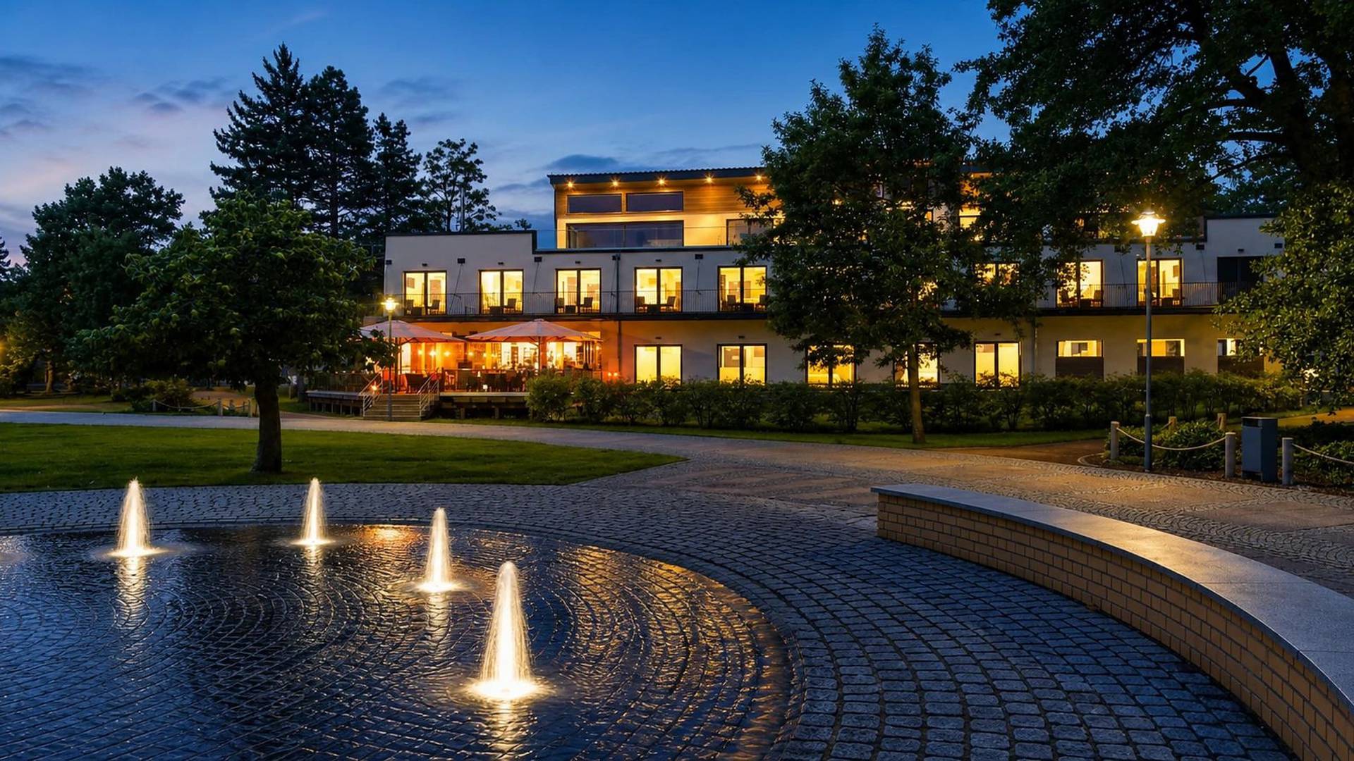 Hotel am Kurpark Zinnowitz am Abend mit beleuchteten Wasserfontänen im Kurpark