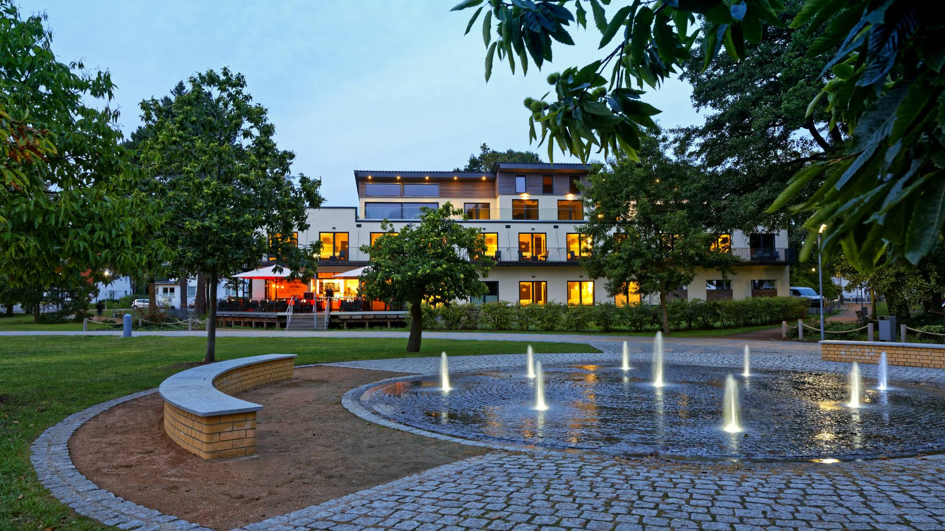 Hotel am Kurpark Zinnowitz in der Abenddämmerung mit Springbrunnen im Kurpark
