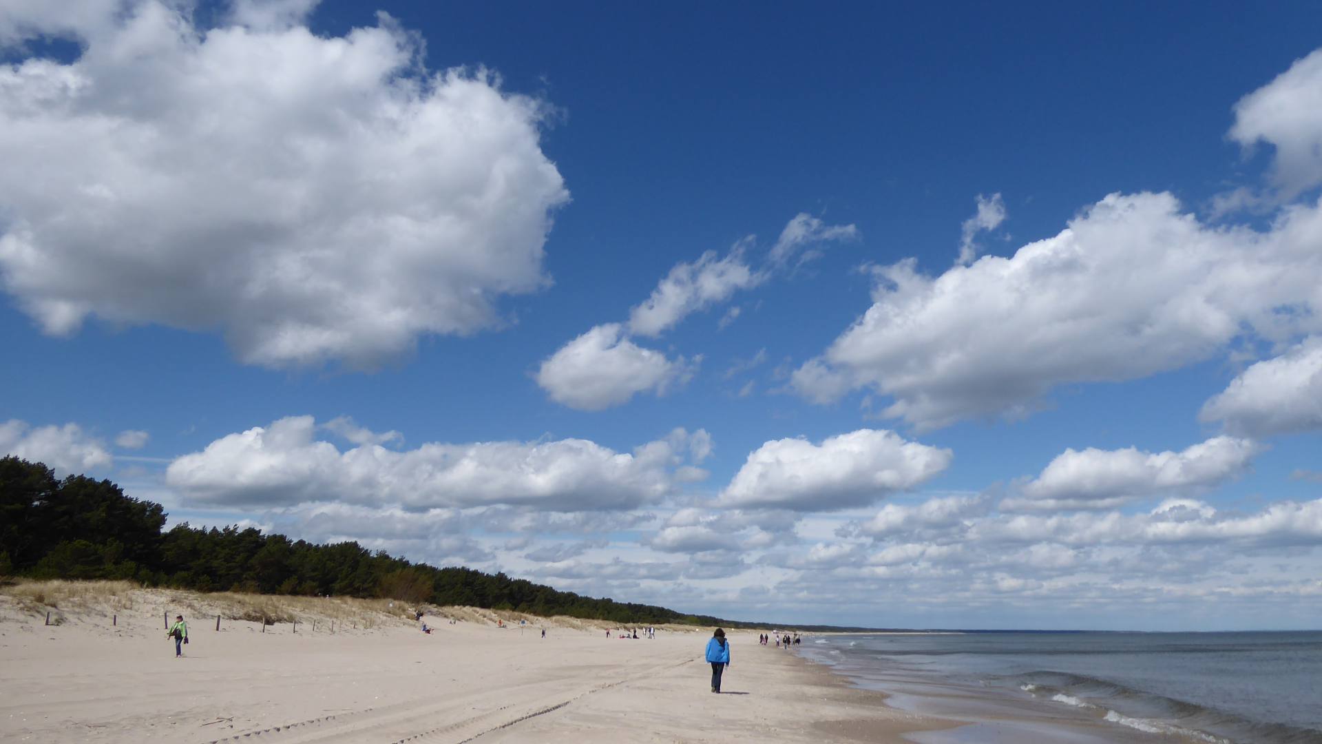 Breiter Ostseestrand bei Zinnowitz mit Spaziergängern unter blauem Himmel