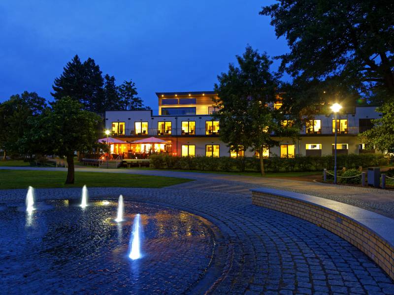 Hotel am Kurpark am Abend mit beleuchtetem Springbrunnen im Kurpark