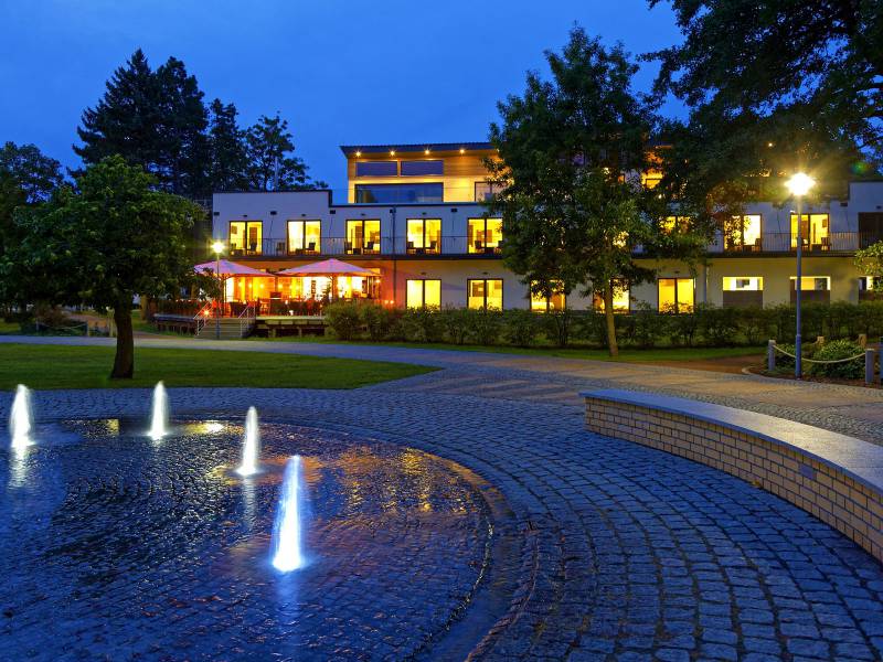 Hotel am Kurpark am Abend mit beleuchtetem Springbrunnen im Kurpark